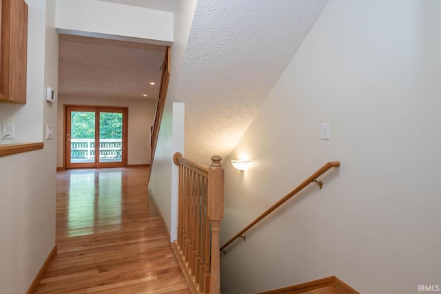 hall with a textured ceiling and light wood-type flooring