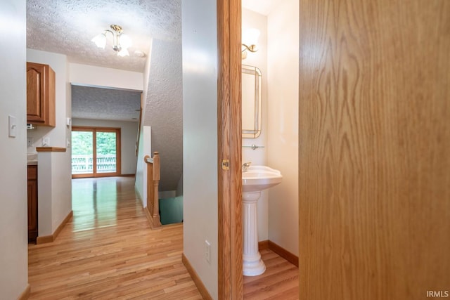 hallway featuring light hardwood / wood-style floors and a textured ceiling