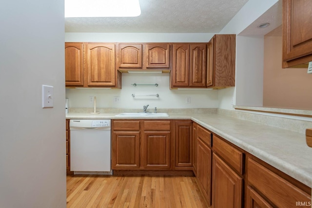 kitchen with white dishwasher, light hardwood / wood-style floors, sink, and a textured ceiling