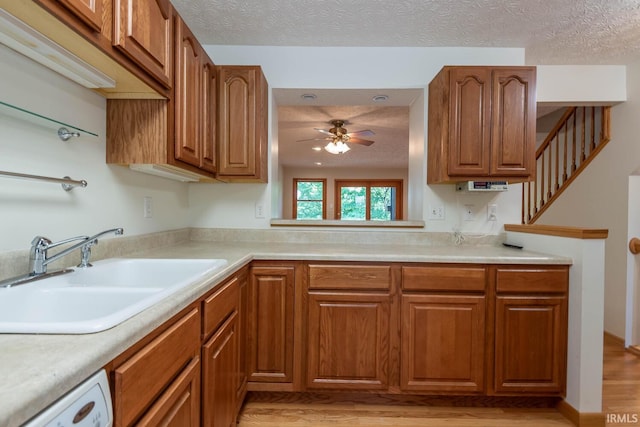 kitchen featuring sink, ceiling fan, white dishwasher, a textured ceiling, and light wood-type flooring