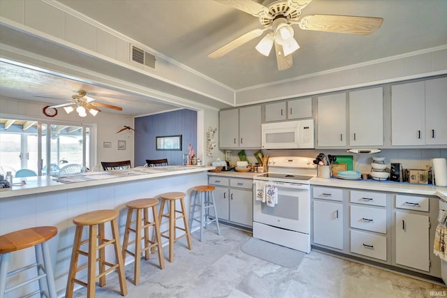 kitchen featuring a breakfast bar area, white appliances, gray cabinets, light tile patterned floors, and ceiling fan