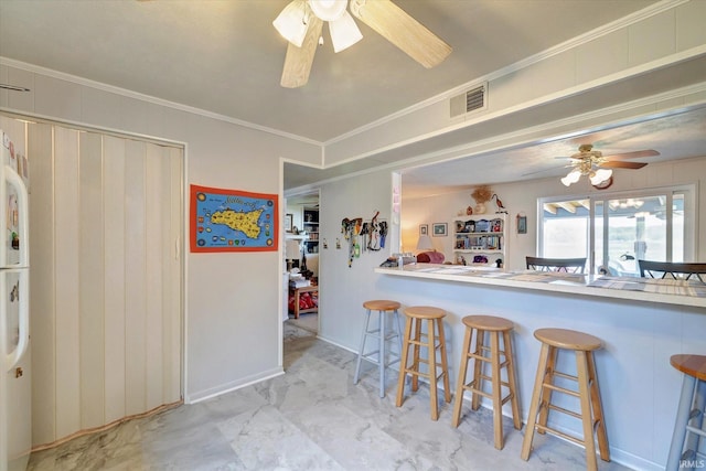 kitchen featuring crown molding, a breakfast bar, and ceiling fan