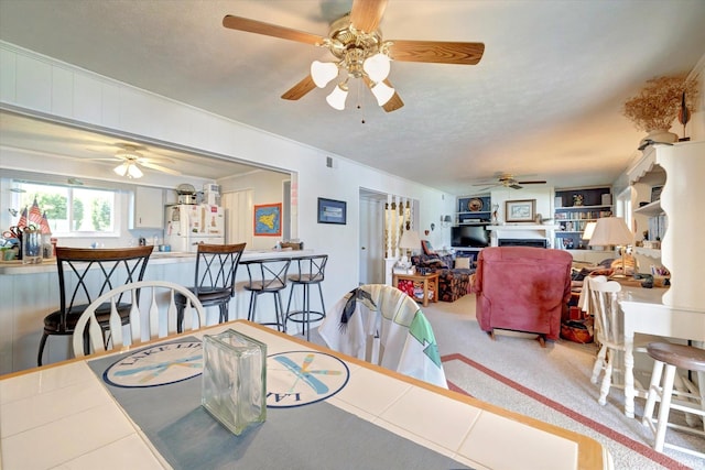 carpeted dining area with ceiling fan