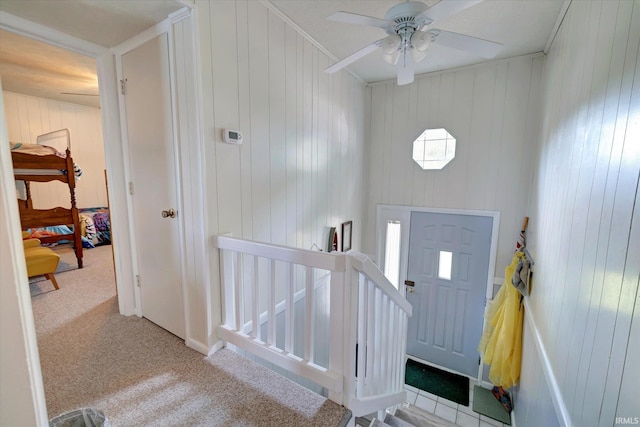 foyer entrance featuring carpet flooring, crown molding, and ceiling fan