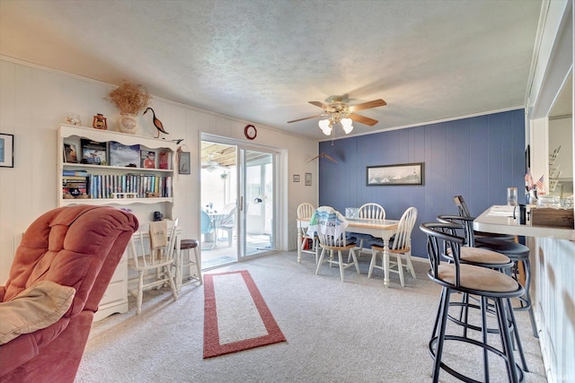 carpeted dining space with ornamental molding, a textured ceiling, and ceiling fan