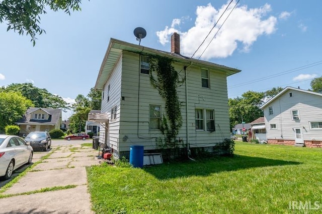 view of property exterior featuring a chimney, a residential view, and a lawn