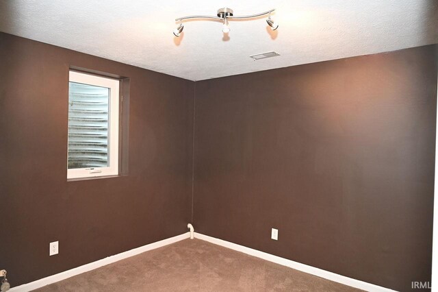 carpeted empty room with a textured ceiling and track lighting