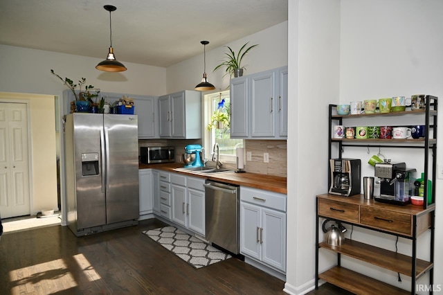 kitchen featuring stainless steel appliances, sink, pendant lighting, backsplash, and dark hardwood / wood-style floors