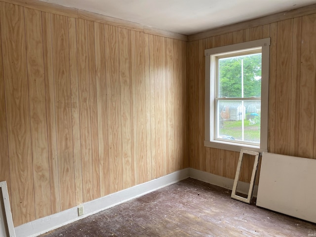 spare room featuring a healthy amount of sunlight, wood walls, and radiator heating unit