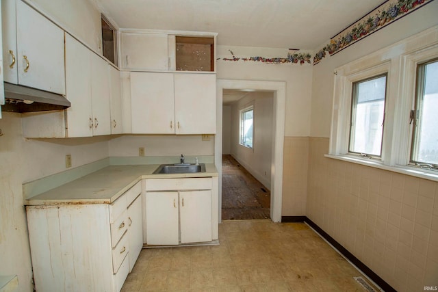 kitchen featuring white cabinetry, a healthy amount of sunlight, tile walls, and sink