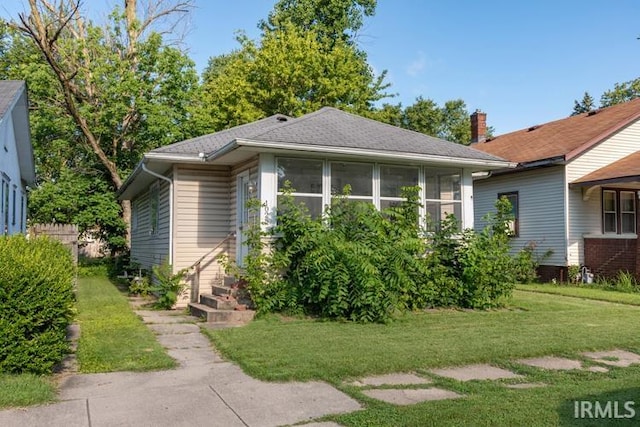 bungalow-style home featuring a sunroom and a front yard