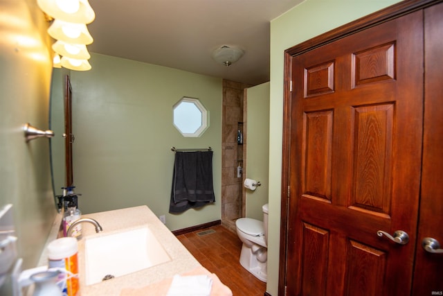 bathroom with toilet, vanity, and wood-type flooring