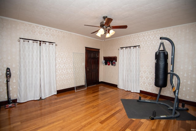 exercise area with ceiling fan, wood-type flooring, and ornamental molding