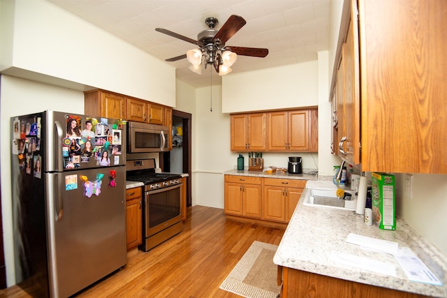 kitchen with ceiling fan, sink, appliances with stainless steel finishes, and light hardwood / wood-style floors