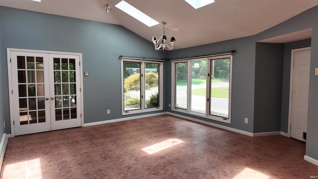 tiled empty room with lofted ceiling with skylight, french doors, and a notable chandelier