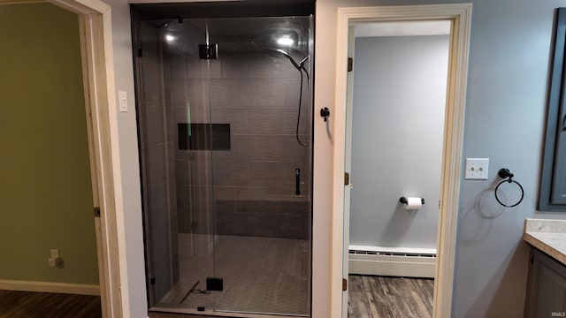 bathroom with hardwood / wood-style flooring, a baseboard radiator, vanity, and an enclosed shower