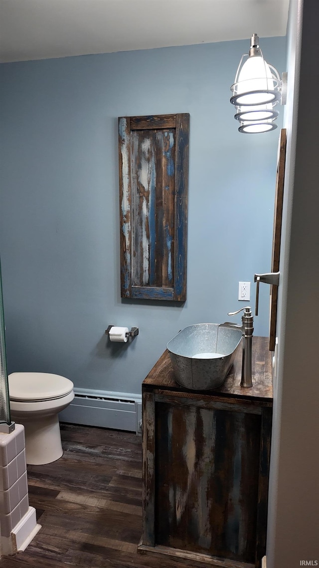 bathroom with a baseboard radiator, vanity, wood-type flooring, and toilet