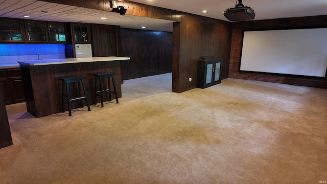 cinema featuring indoor bar, light colored carpet, and wooden walls