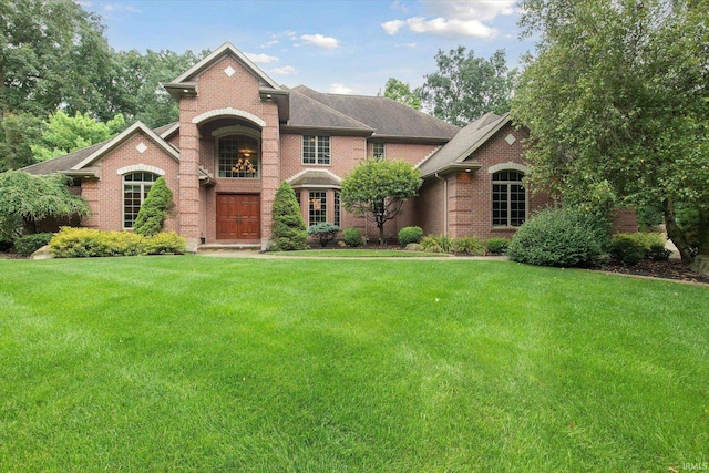 view of front of home with brick siding, a front yard, and a shingled roof