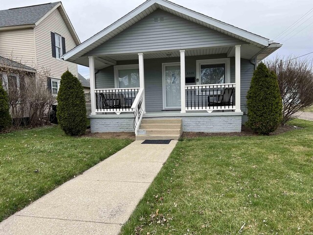 bungalow featuring covered porch and a front yard