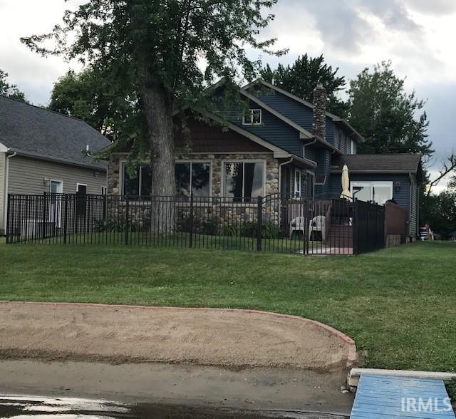 view of front of house featuring stone siding, a fenced front yard, and a front yard