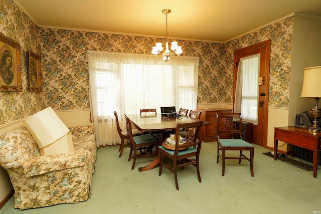 dining space with carpet floors, ornamental molding, and a notable chandelier