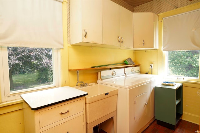 clothes washing area featuring cabinets, washer and dryer, and a healthy amount of sunlight