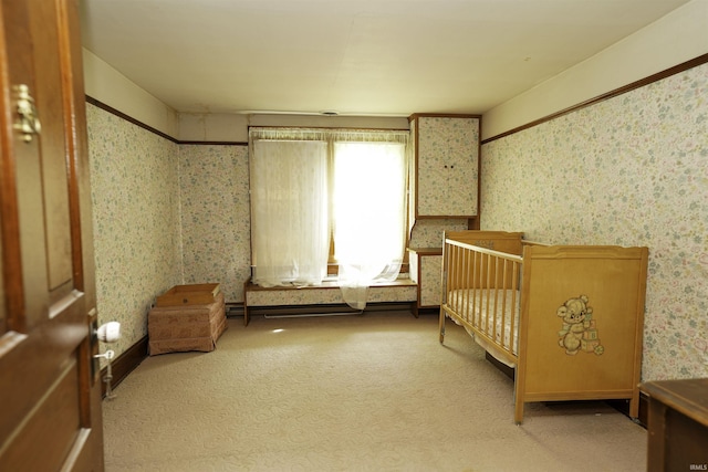 unfurnished bedroom with carpet flooring, a crib, and wallpapered walls