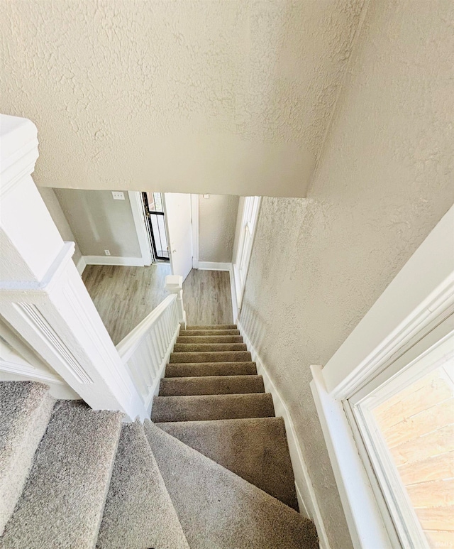 stairs featuring a textured ceiling and hardwood / wood-style flooring