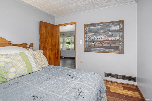 bedroom with wood finished floors, visible vents, and baseboards