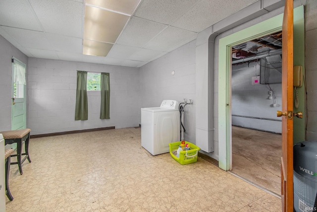 basement featuring tile patterned floors, concrete block wall, washer / clothes dryer, and a drop ceiling