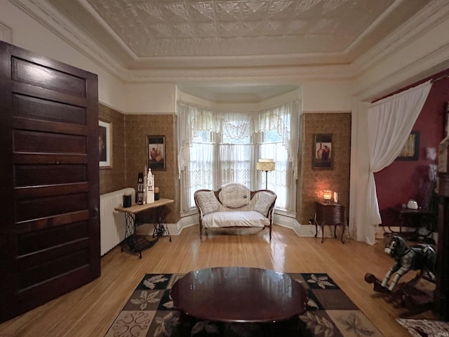 living room with a raised ceiling, ornamental molding, hardwood / wood-style floors, and radiator heating unit