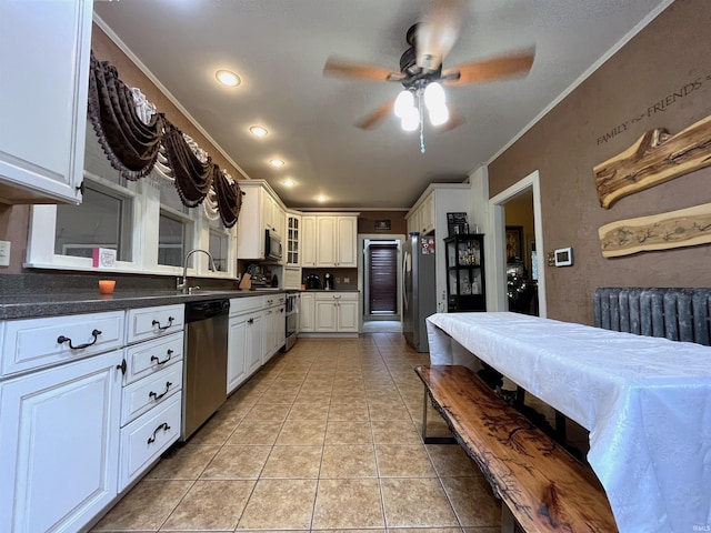 kitchen with white cabinetry, light tile patterned floors, ceiling fan, stainless steel appliances, and ornamental molding