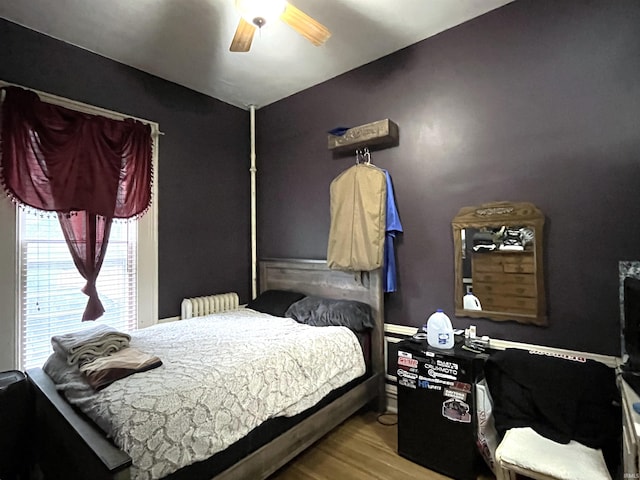 bedroom with radiator heating unit, light hardwood / wood-style flooring, and ceiling fan