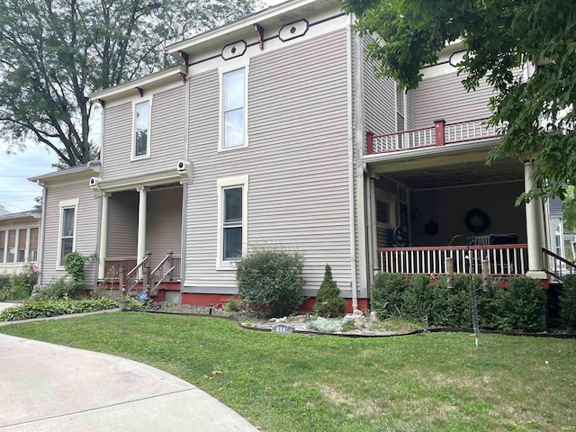 view of front of house with a balcony, covered porch, and a front yard