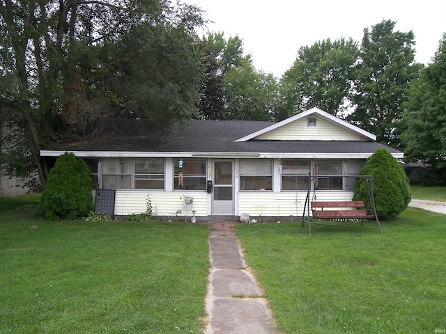 ranch-style home featuring a shingled roof, a sunroom, and a front lawn