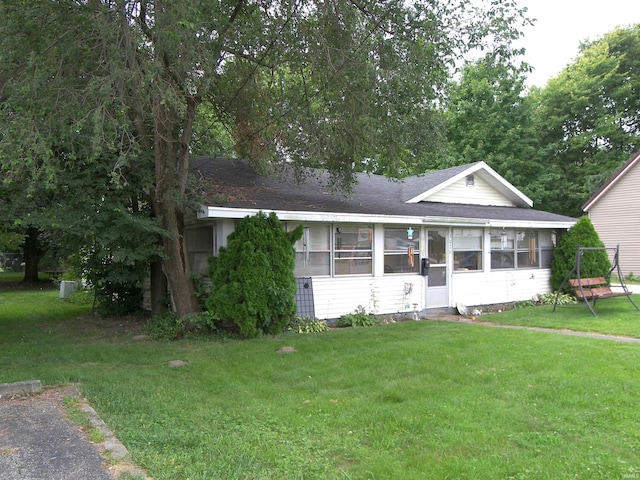 view of front of house with a sunroom and a front lawn