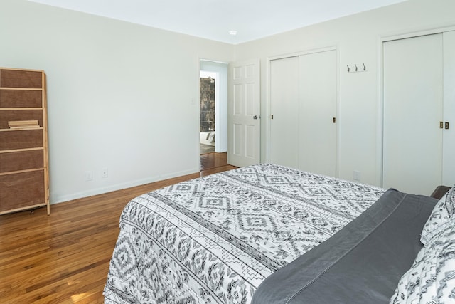 bedroom with multiple closets and hardwood / wood-style floors