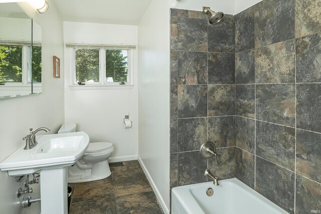 bathroom featuring tiled shower / bath combo, toilet, and tile patterned floors