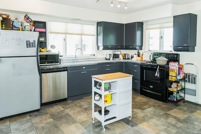 kitchen with track lighting, stainless steel appliances, wooden counters, sink, and tile patterned flooring