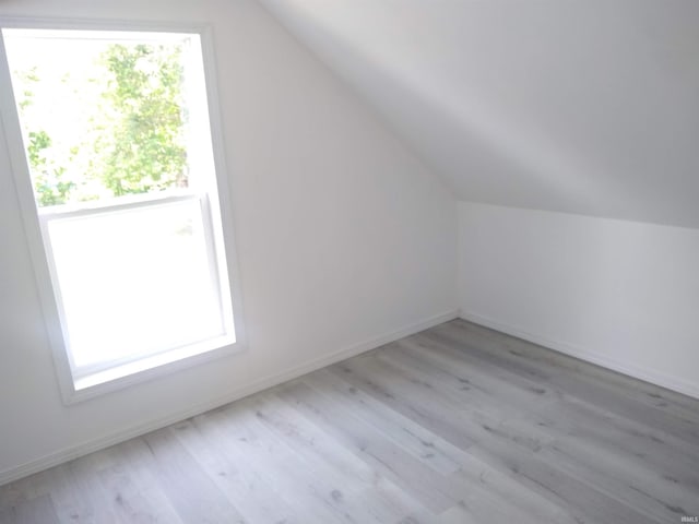 additional living space with light hardwood / wood-style floors and lofted ceiling