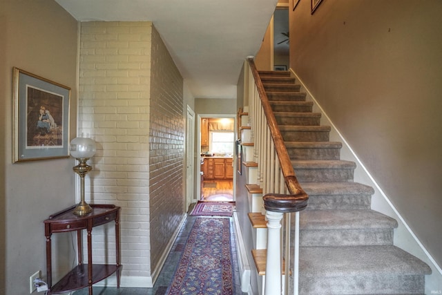 stairs featuring brick wall and hardwood / wood-style flooring