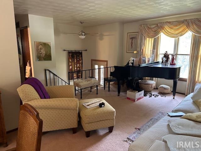 living room with a textured ceiling, ceiling fan, and light colored carpet