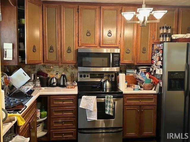 kitchen featuring appliances with stainless steel finishes, hanging light fixtures, and decorative backsplash