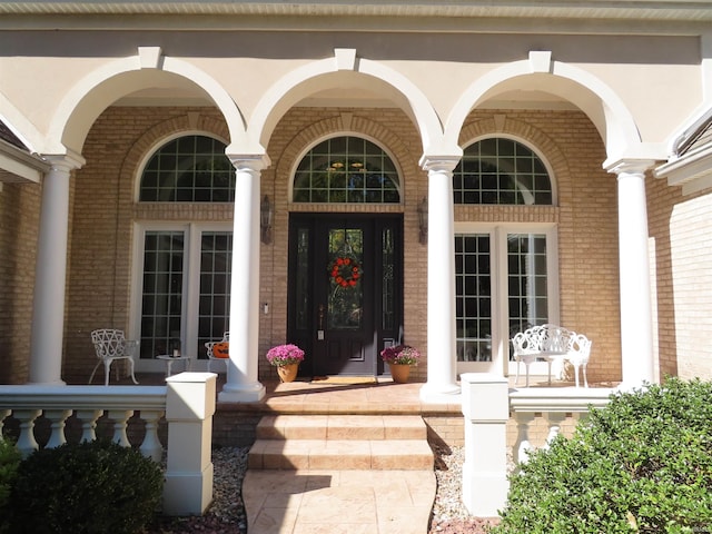 property entrance with covered porch and brick siding