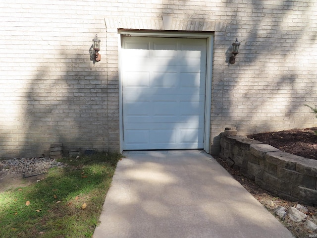 view of exterior entry featuring a garage, driveway, and brick siding