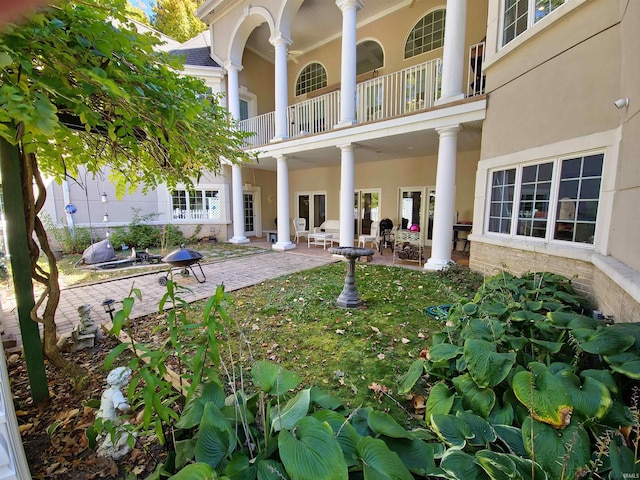 rear view of property featuring a patio area, a balcony, and stucco siding