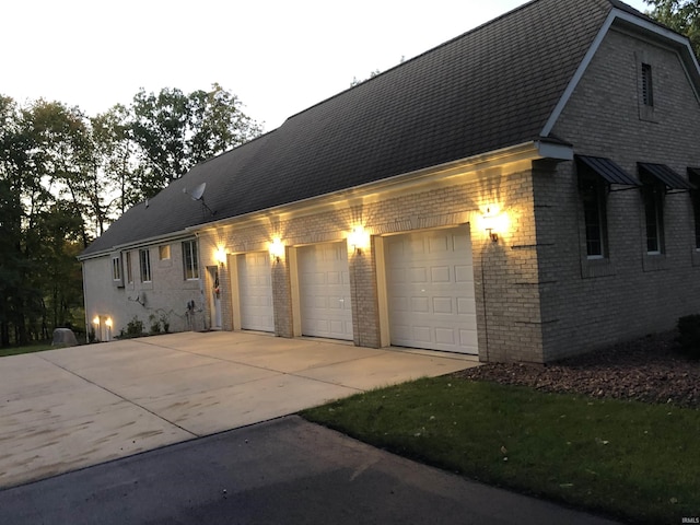 view of front facade with concrete driveway, brick siding, and roof with shingles