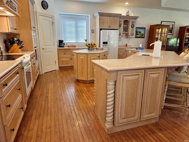 kitchen with white appliances, light wood-style floors, glass insert cabinets, a center island, and under cabinet range hood