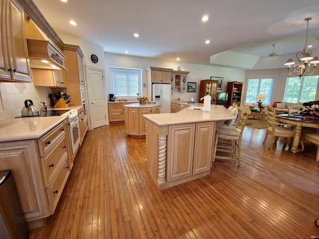 kitchen featuring white appliances, light countertops, a center island, hardwood / wood-style floors, and an inviting chandelier